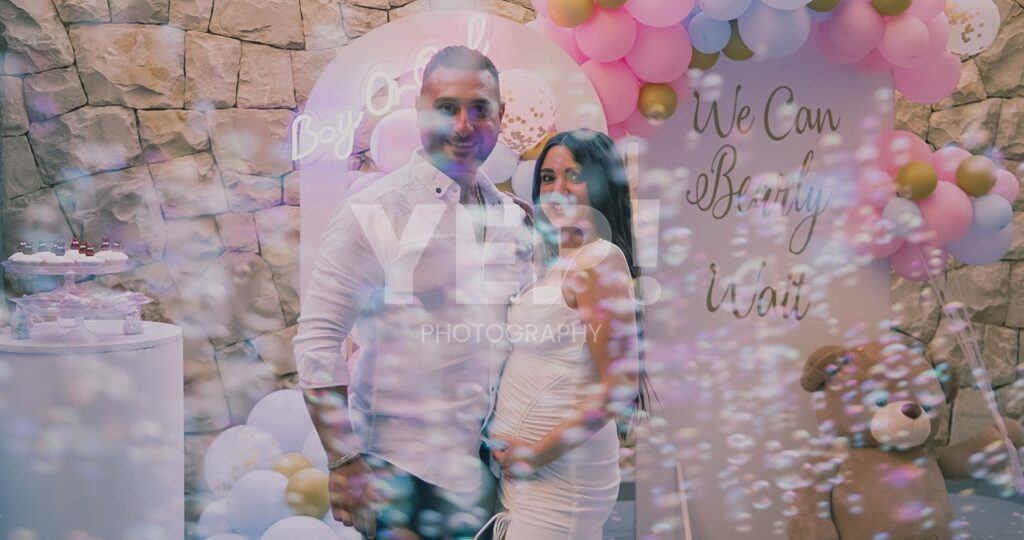 07-babyshower-event-pink-blue-yep-yepphotography Excited parents-to-be celebrating their baby's gender reveal, surrounded by festive pink and blue decorations or elements.