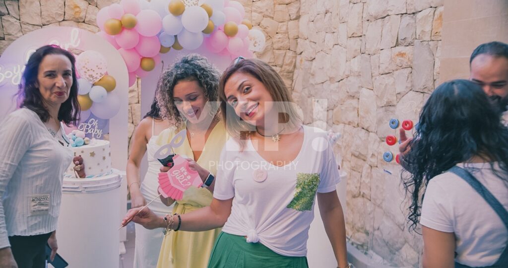 08-babyshower-event-pink-blue-yep-yepphotography Excited parents-to-be celebrating their baby's gender reveal, surrounded by festive pink and blue decorations or elements.