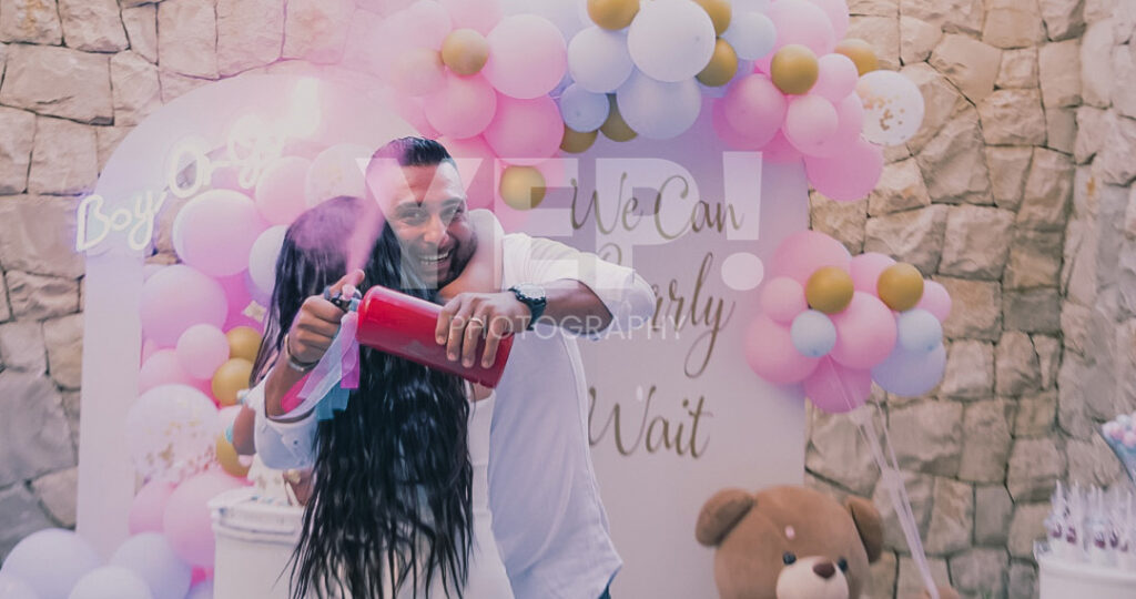 11-babyshower-event-pink-blue-yep-yepphotography-2 Excited parents-to-be celebrating their baby's gender reveal, surrounded by festive pink and blue decorations or elements.