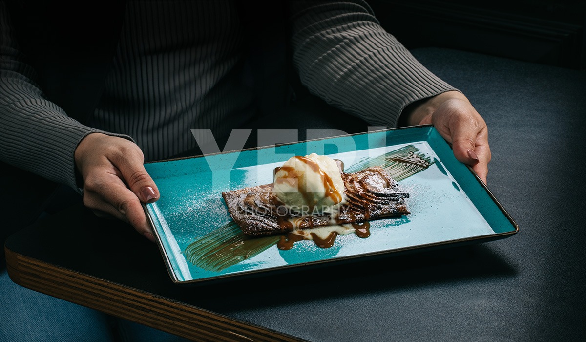 linascafe-linas-yep-yepphotography-gabrielsphotography-26 A freshly prepared healthy meal displayed on a dark surface in a modern restaurant environment, illuminated by soft ambient lighting.