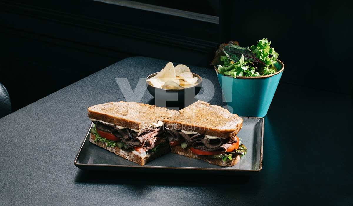 linascafe-linas-yep-yepphotography-gabrielsphotography-28 A freshly prepared healthy meal displayed on a dark surface in a modern restaurant environment, illuminated by soft ambient lighting.