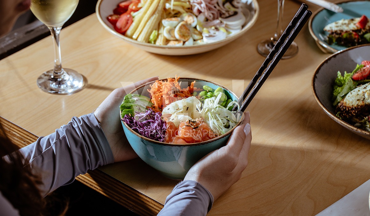 linascafe-linas-yep-yepphotography-gabrielsphotography-40 A freshly prepared healthy meal displayed on a dark surface in a modern restaurant environment, illuminated by soft ambient lighting.