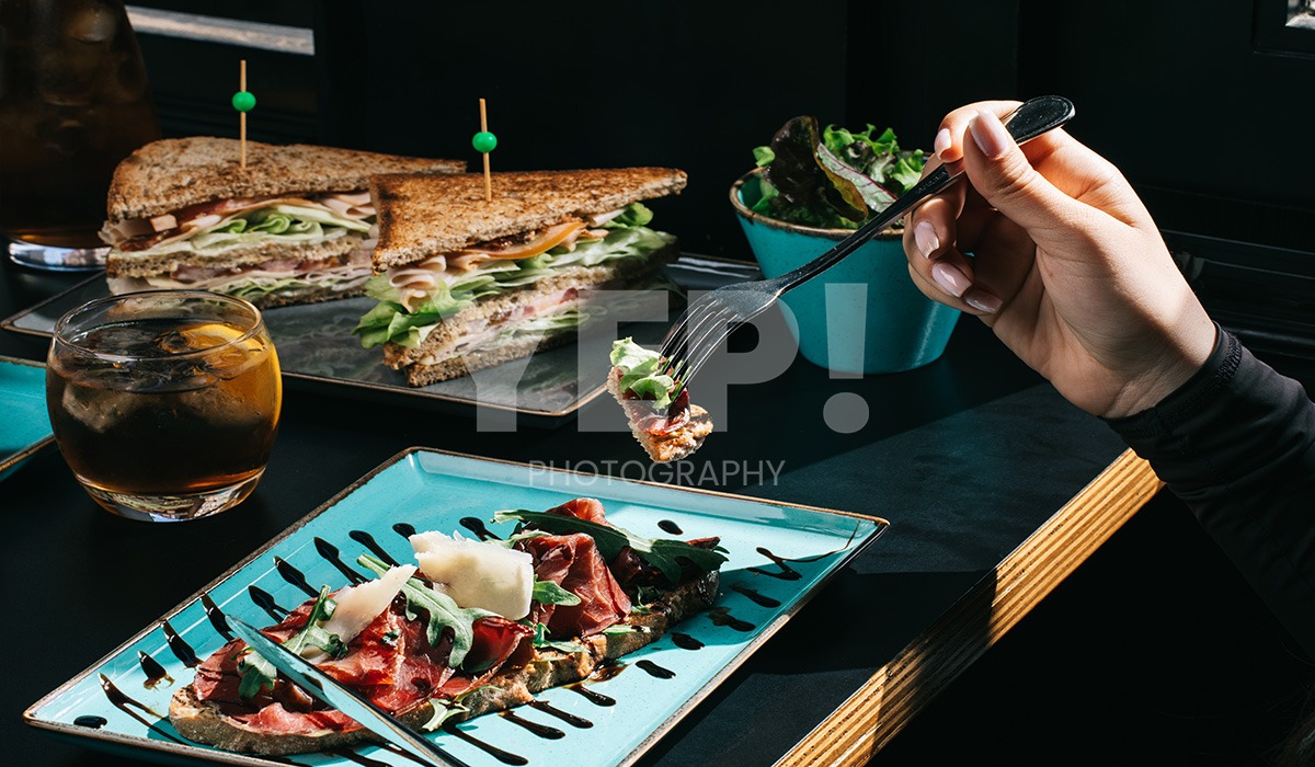 linascafe-linas-yep-yepphotography-gabrielsphotography-42 A freshly prepared healthy meal displayed on a dark surface in a modern restaurant environment, illuminated by soft ambient lighting.